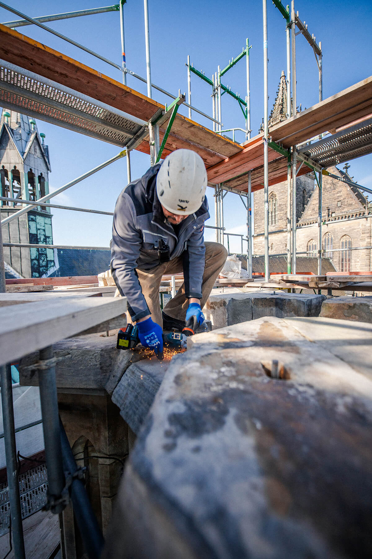 Steinmetz in der Denkmalpflege arbeitet am Magdeburger Dom Steinmetz am Magdeburger Dom flext ein Metallteil ab